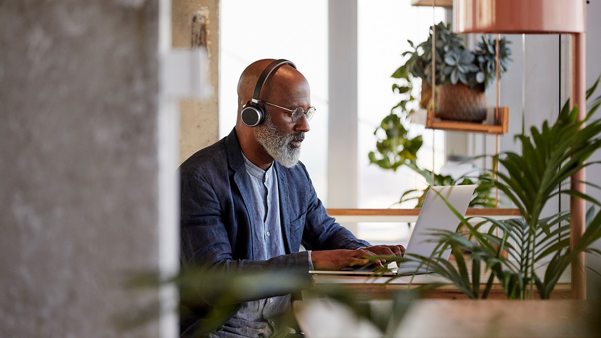 Man working on a laptop surrounded by house plants 