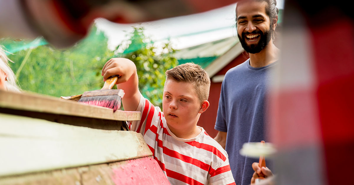 A man helping a child paint a shed as part of a community outreach programme A man helping a child paint a shed as part of a community outreach programme