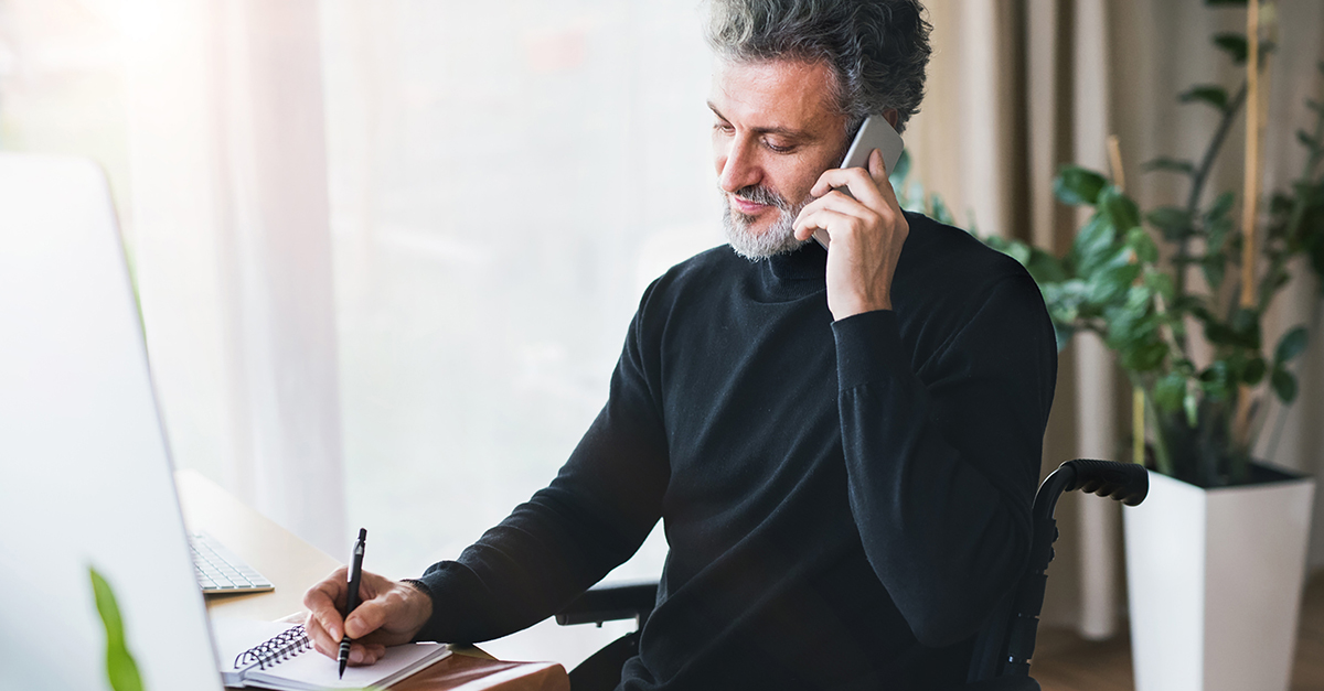 Man in wheelchair making a call from his home office
