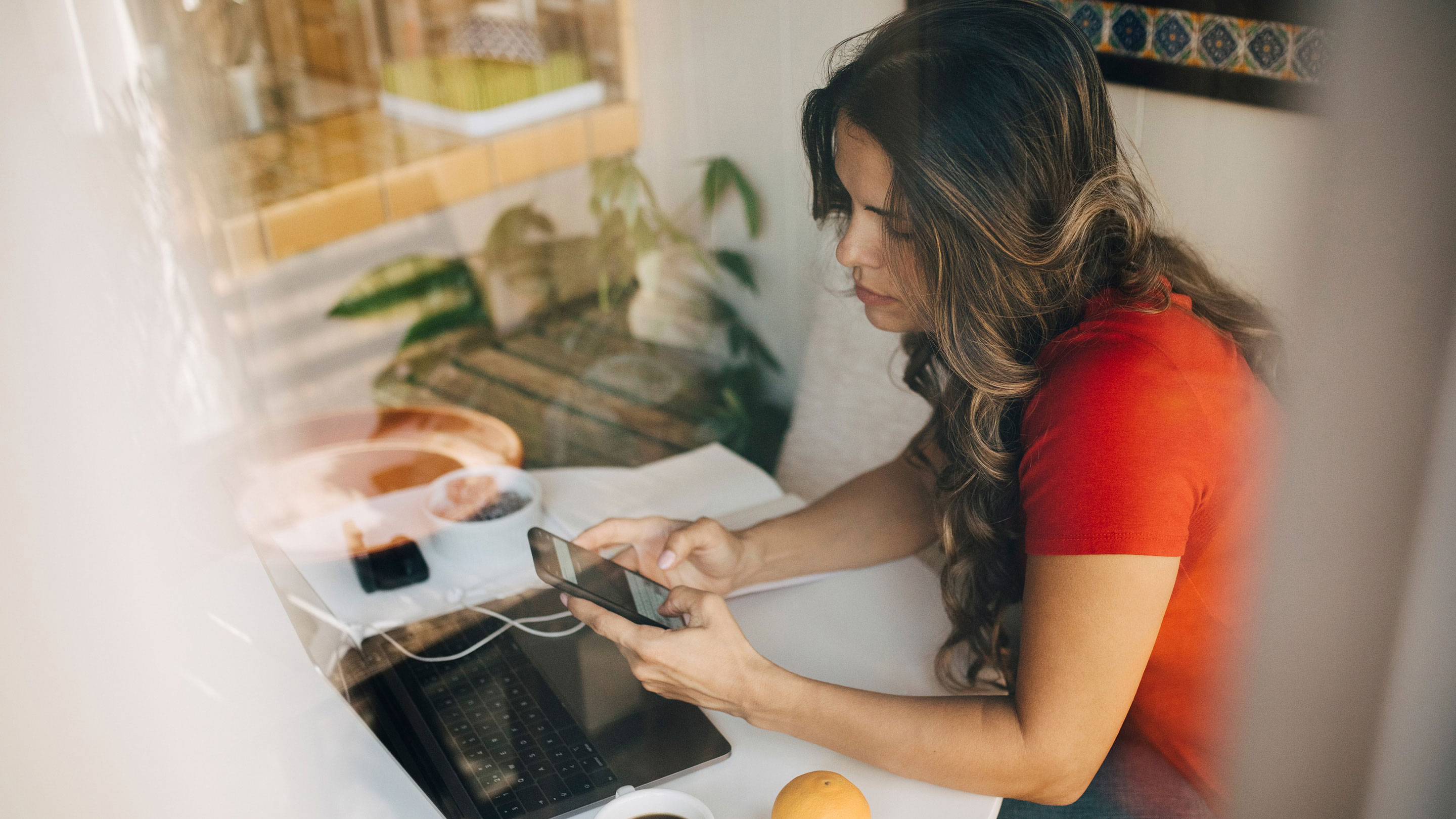 Woman in red top checking her phone in her home office