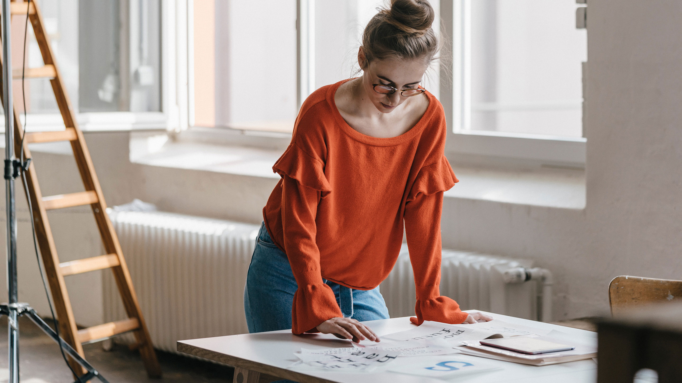 Women wearing a red top reviewing lettering in a studio Women wearing a red top reviewing lettering in a studio